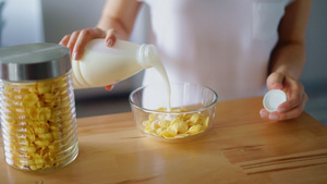 妇女双手将牛奶倒入玉米片的玻璃碗21秒视频