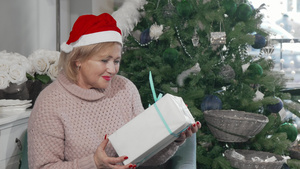穿着圣诞礼帽的快乐老女人带着圣诞节礼物9秒视频