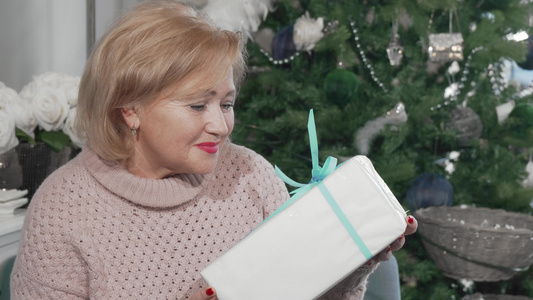 高级女士对着相机微笑手握着圣诞节的礼物视频