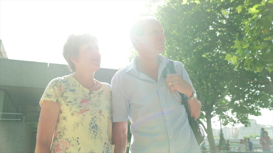 活跃的高级老人旅游情侣在隆登走在太阳下背斜线视频