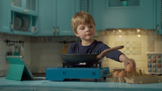学龄前男孩煮炒鸡蛋看着平板电脑上的在线食谱独自站在视频