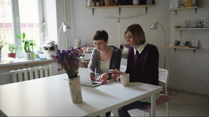 两名坐在桌边并使用笔记本在线订购的年轻妇女12秒视频