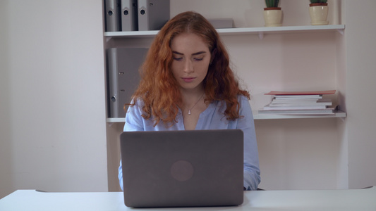有卷发的年轻女人工作在PC视频