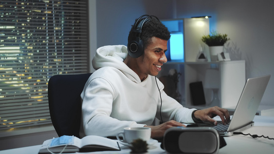 近距离拍摄戴耳机的男人在晚上在电脑上玩游戏视频