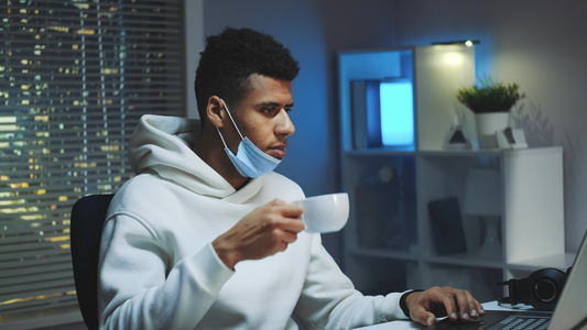 英俊的多种族男子中中枪喝咖啡晚上在电脑上打工视频