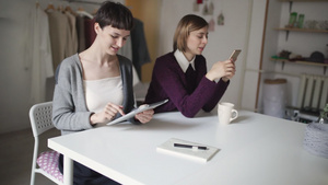 两名使用平板和手机坐在桌边的女学生8秒视频