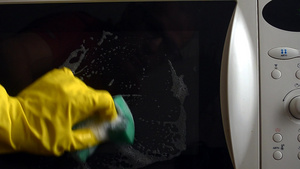 戴防护手套的男子用海绵和溶液清洗微波炉的闭锁门12秒视频