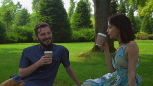 一对年轻的情侣坐在公园的地上喝咖啡15秒视频