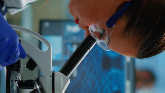 垂直视频在医学实验室的显微镜下观察的科学家肖像视频