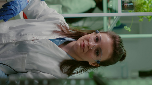 垂直视频在制药实验室工作的身着白衣的化学妇女肖像画视频