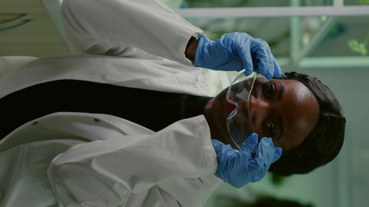 垂直视频非洲生物学家在白色大衣上望着相机的肖像视频