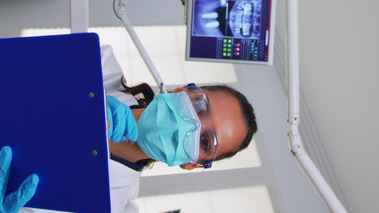垂直视频牙科医生询问病人和作笔记;牙医医生视频