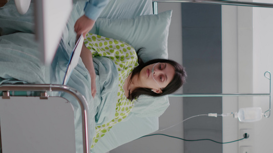 垂直视频执业专家检查住院病人在床上躺着的生病妇女【竖版】视频