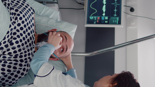 垂直视频生病的男子躺在床上而女医护人员却用氧气罩子【竖版】视频