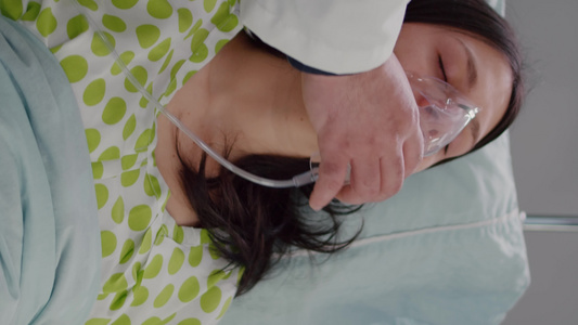 垂直视频关闭医生给生病的妇女戴氧气面具的医生视频