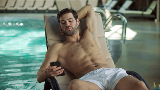 在游泳池边使用手机的男人[品牌手机]视频