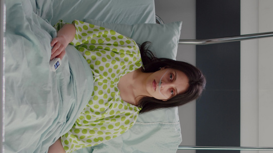 垂直视频有鼻氧管的生病妇女对躺在床上的照相机进行监视视频