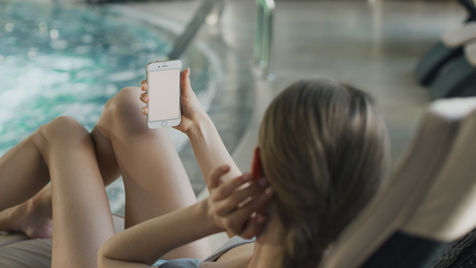 在泳池附近的看手机的年轻女人[相邻地方]视频