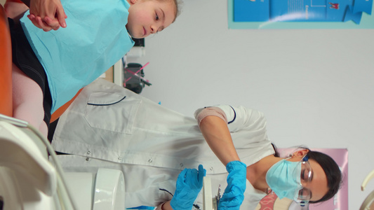 垂直视频小儿牙医面罩检查一个小女孩的牙科健康视频