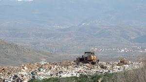 一台推土机拖拉机将垃圾从一座城市垃圾场的山上推出来14秒视频