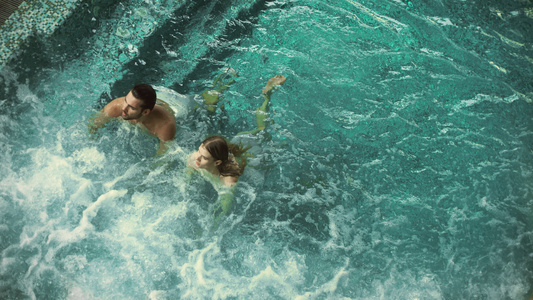 放松可爱的情侣在游泳池享受视频