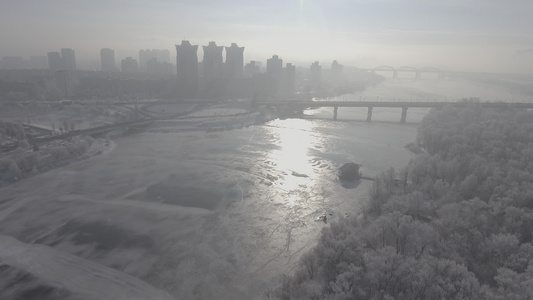 雪中城市飞越森林和河流远处可以看到桥和日出视频