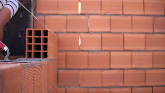 建筑工人在建筑工地铺砖建砖形成砖墙视频