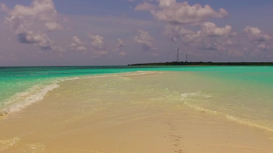 以蓝水和白沙底背景的白色海水在海浪附近进行并紧贴着视频