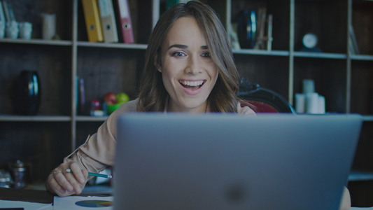 微笑的女商务人士看着笔记本电脑屏幕享受好消息[家庭用户]视频