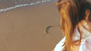 在奇异的日落时在湿沙上画出心型形状的女孩16秒视频