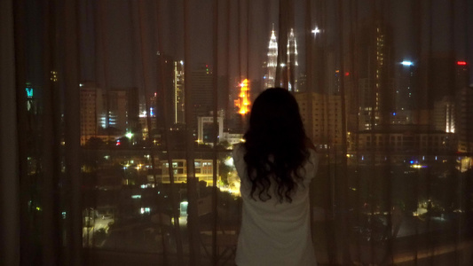 女孩打开窗帘张开夜市令人惊叹的景色视频