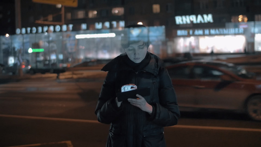 在繁忙的夜间城市使用数字石板的年轻妇女视频