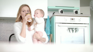 母亲喝着咖啡在厨房抱小婴儿14秒视频