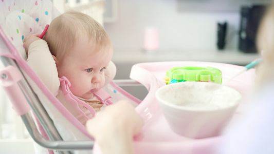 婴儿和玩具坐在椅子上吃纯净的婴儿母亲用勺子喂婴儿视频