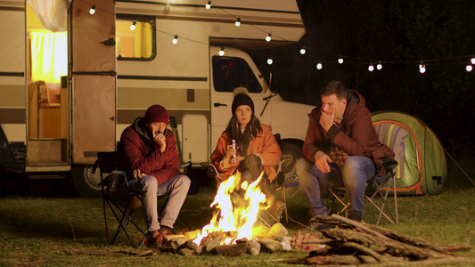 一群朋友在秋天寒冷的夜晚聚集在营火周围视频