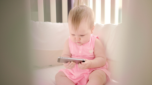 婴儿与智能手机玩游戏在上看卡通的小女孩视频