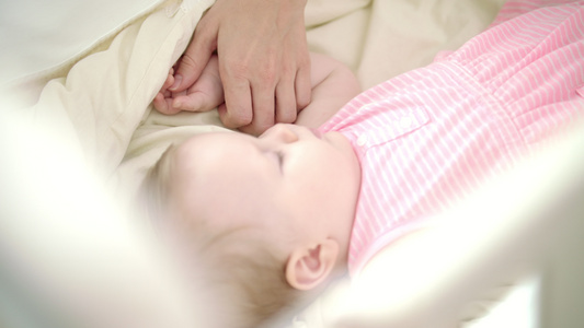 母亲拉着睡在床上的小婴儿的手视频