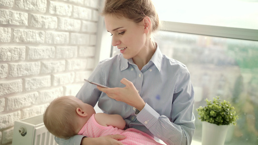 穿着衬衫的漂亮女人拍着孩的移动照片妈拍着婴儿的照片视频
