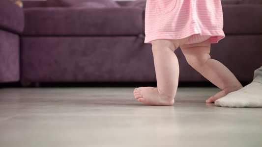 女婴正在迈出人生的第一步婴儿学习走路小脚步视频