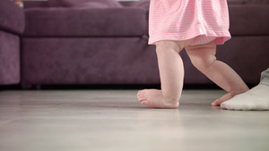 女婴正在迈出人生的第一步婴儿学习走路小脚步14秒视频