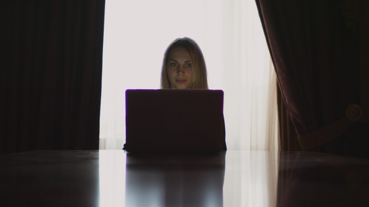 年轻女性打开笔记本电脑坐在桌子上视频