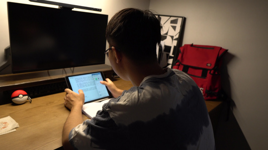 夜晚大学生在宿舍公寓使用平板电脑学习备考视频