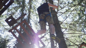 身着安全装备的年轻人在夏日攀爬公园高处绳索上行走17秒视频
