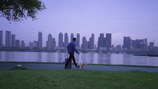 4k素材慢镜头升格拍摄城市江滩街景拖着行李箱遛狗的男人视频