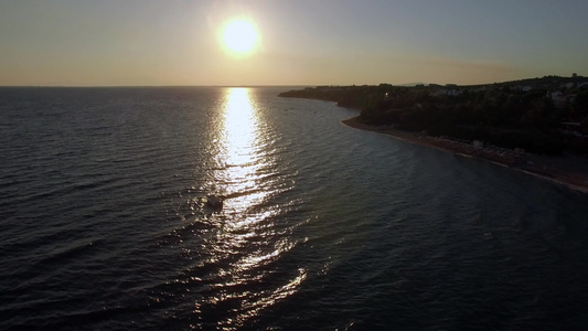 日落时有船只在海岸和海面上空飞行视频
