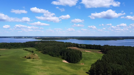无人机从绿色草地上起飞观察蓝湖和白云的景象空中摄影视频
