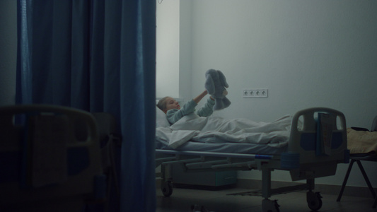 生病的女孩独自躺在病床上心烦意乱玩毛绒玩具视频