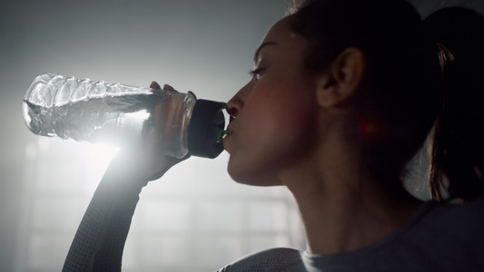 女孩从健身瓶里喝水站立在体育俱乐部的女运动员视频