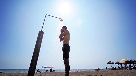 男子在沙滩上洗澡对着太阳电影镜头慢动作冲洗身体视频