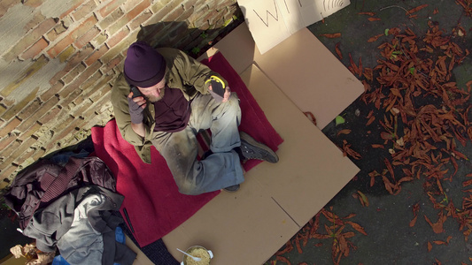 无家可归的人坐在太阳下拿着太阳能电池视频
